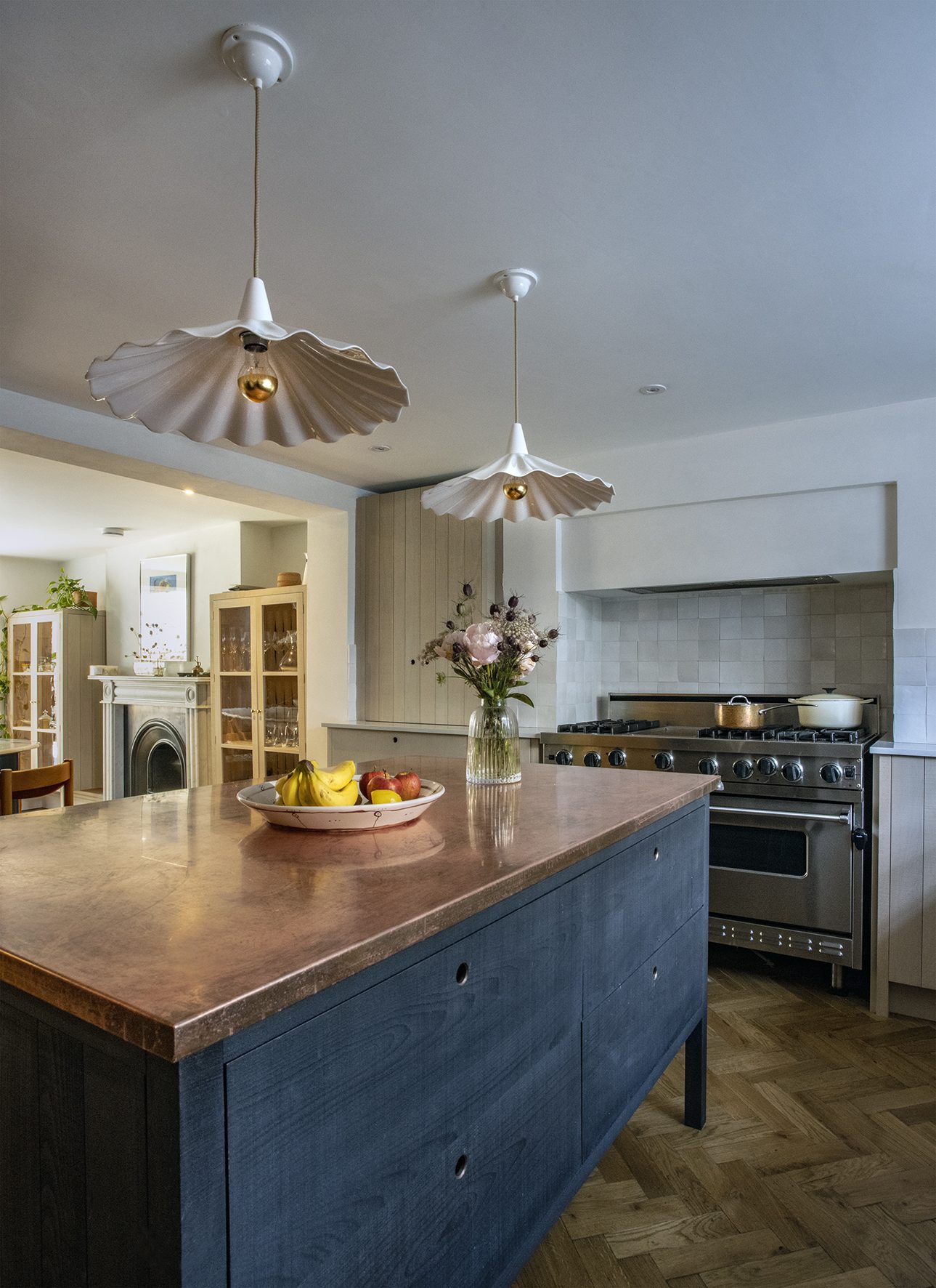 Kitchen with a copper-topped island, scalloped ceramic pendants and herringbone floor, designed by Make My House Home